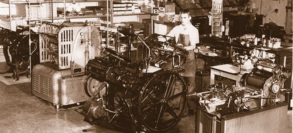 Historic printing press operator working with large industrial machine