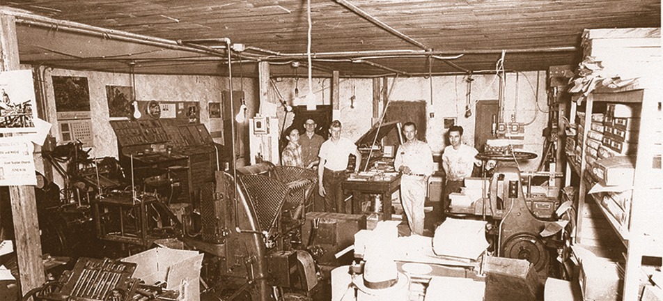 Historic print shop with workers and large printing equipment