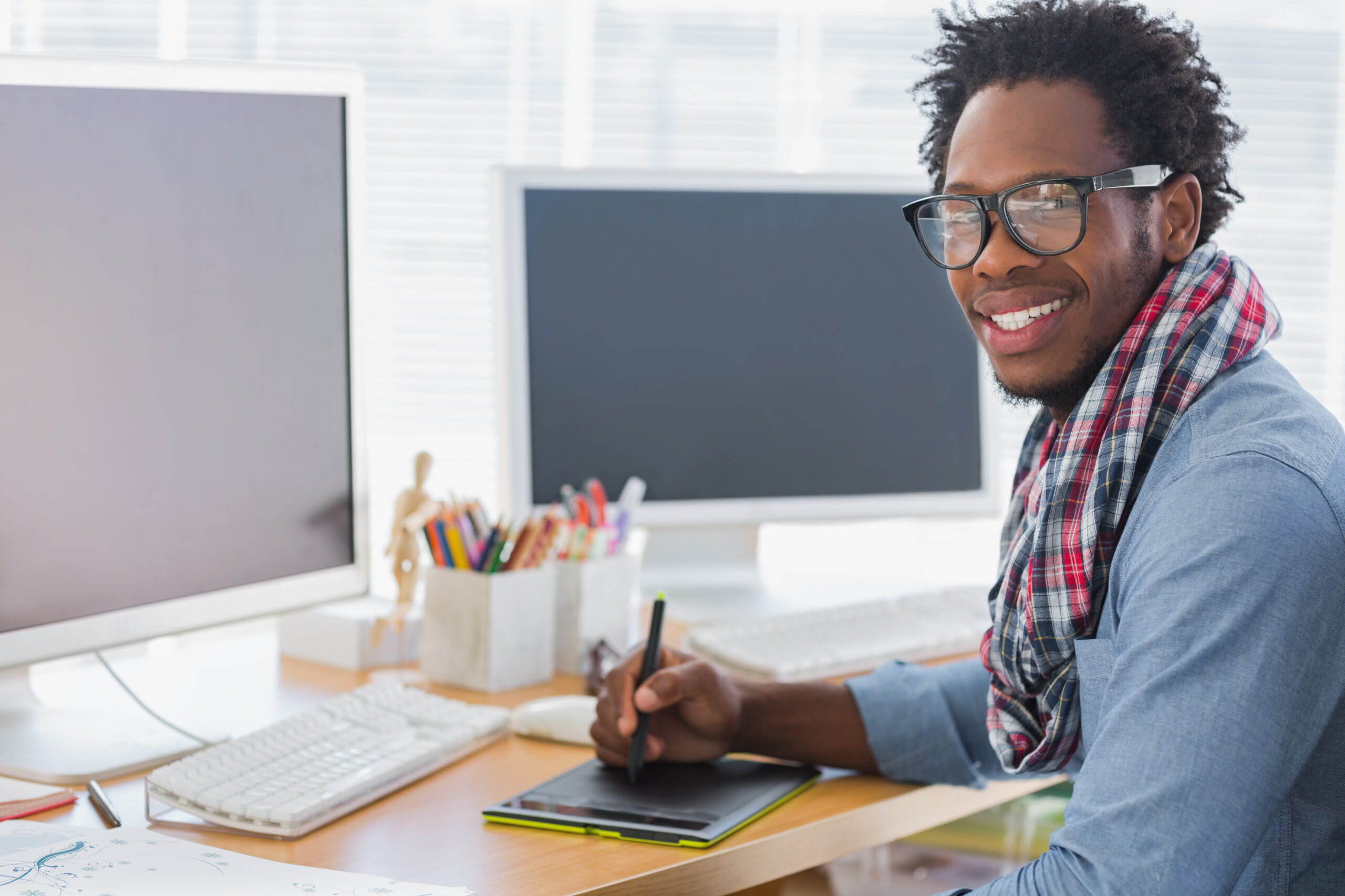 Graphic designer using digital drawing tablet at computer workstation